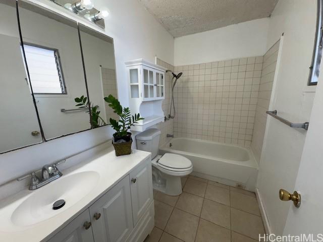 bathroom featuring tile patterned floors, toilet, a textured ceiling, washtub / shower combination, and vanity