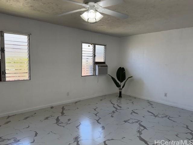 spare room featuring ceiling fan, baseboards, marble finish floor, and a textured ceiling