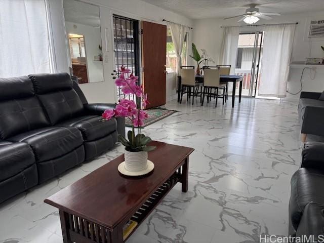 living room with a wall mounted air conditioner, marble finish floor, a textured ceiling, and a ceiling fan