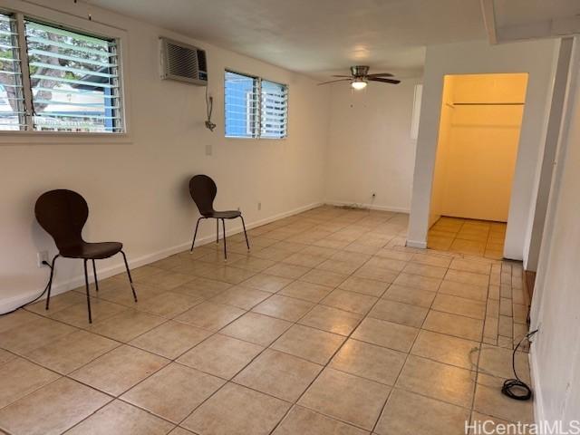 interior space featuring light tile patterned flooring, an AC wall unit, baseboards, and ceiling fan