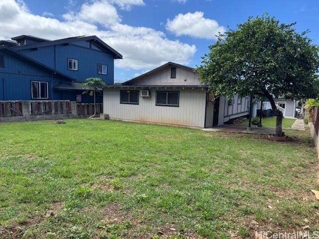 rear view of property with a yard, fence, and a wall mounted air conditioner