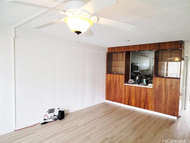 unfurnished living room featuring ceiling fan, wood finished floors, and a textured ceiling