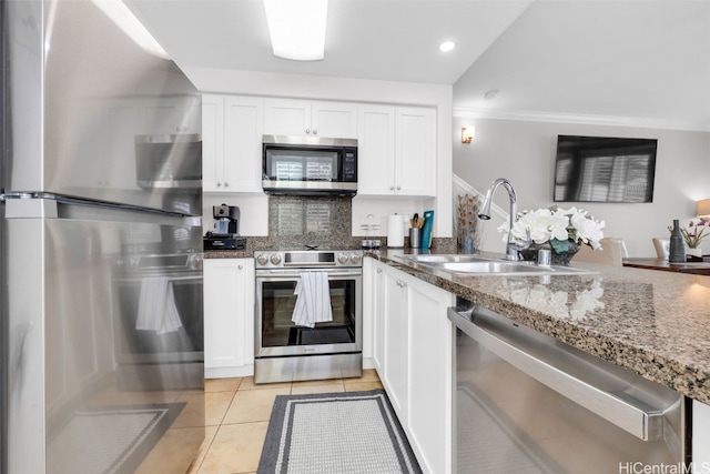 kitchen featuring a sink, white cabinetry, stainless steel appliances, dark stone counters, and light tile patterned flooring