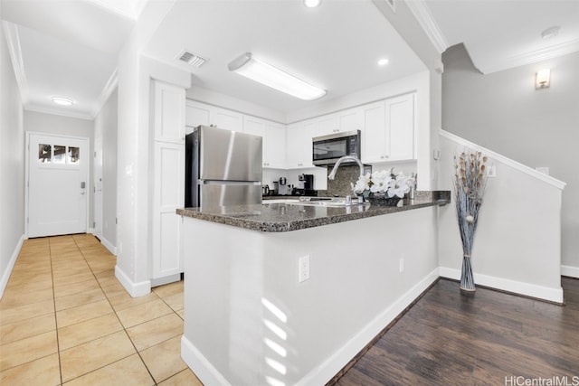 kitchen with visible vents, white cabinetry, appliances with stainless steel finishes, a peninsula, and crown molding