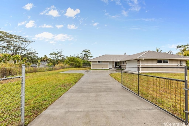 view of front of house featuring a fenced front yard, driveway, metal roof, and a front yard