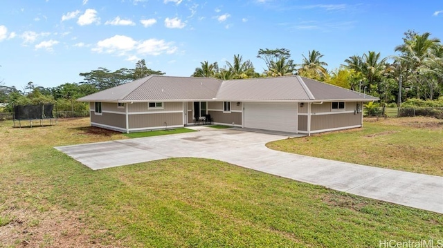 single story home featuring a garage, driveway, a front yard, and a trampoline