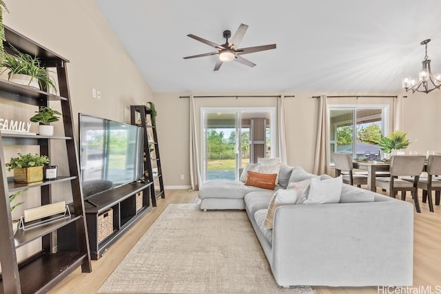 living area with ceiling fan with notable chandelier, wood finished floors, a healthy amount of sunlight, and lofted ceiling