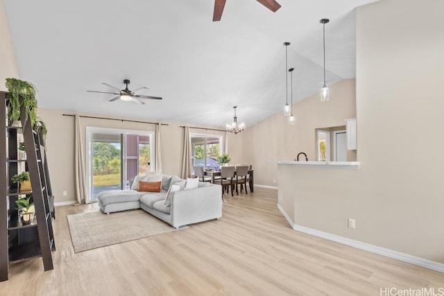 living area with baseboards, lofted ceiling, light wood-style flooring, and ceiling fan with notable chandelier