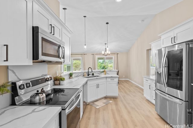 kitchen with lofted ceiling, a peninsula, a sink, stainless steel appliances, and white cabinets