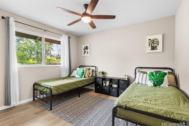 bedroom featuring a ceiling fan, baseboards, and wood finished floors