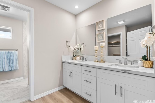 full bath featuring a sink, visible vents, baseboards, and double vanity