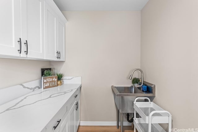 laundry room with light wood-style flooring, baseboards, and a sink