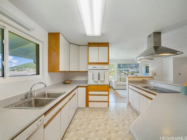 kitchen featuring a sink, white appliances, white cabinets, island range hood, and light floors