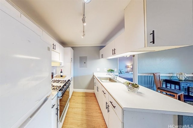 kitchen with light wood-type flooring, a sink, freestanding refrigerator, light countertops, and gas range