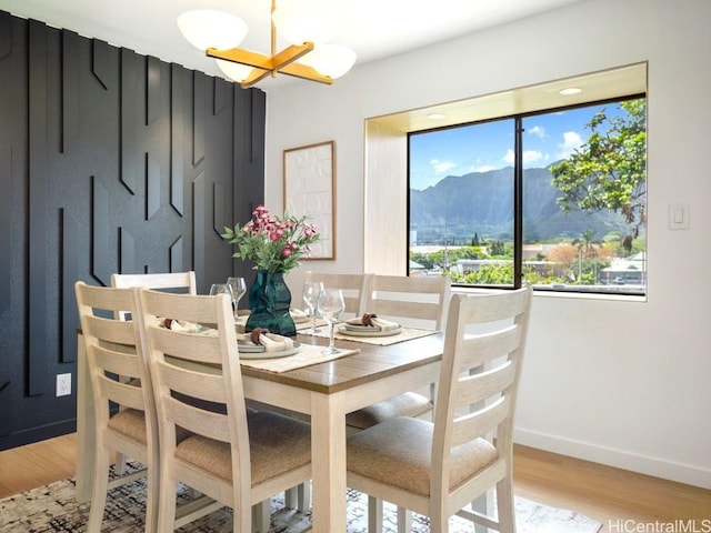 dining space with a notable chandelier, baseboards, a mountain view, and light wood-type flooring