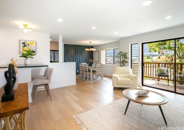 living area with recessed lighting, baseboards, and light wood-style flooring