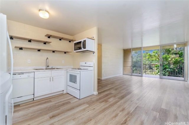 kitchen with white appliances, light countertops, light wood finished floors, and a sink