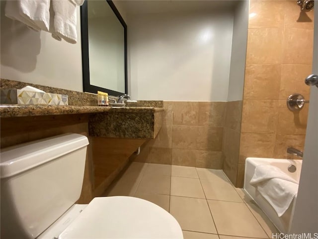 bathroom with tile patterned floors, toilet, tile walls, and wainscoting