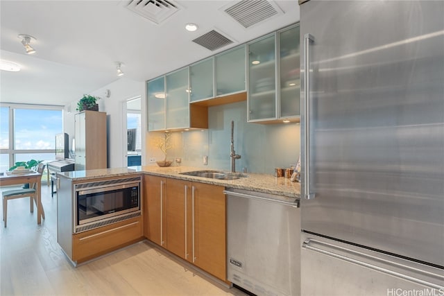 kitchen featuring light stone counters, visible vents, appliances with stainless steel finishes, and a sink