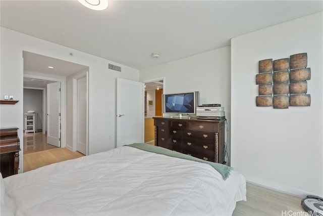 bedroom with visible vents, baseboards, and light wood finished floors