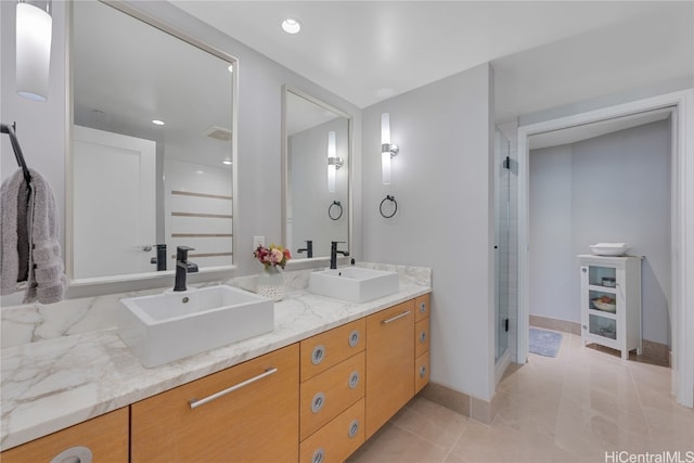 bathroom featuring a shower stall, double vanity, tile patterned floors, and a sink