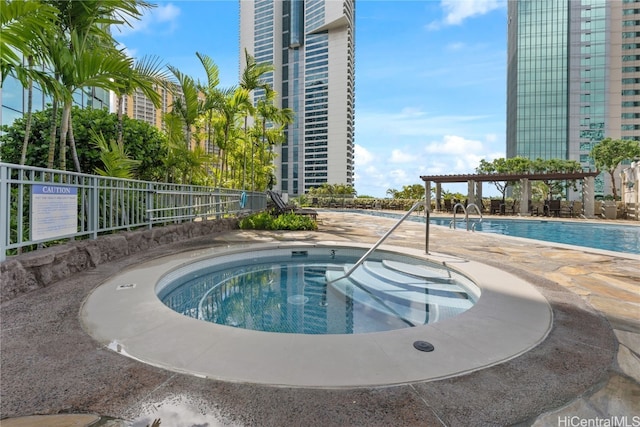 community pool with a pergola, a hot tub, and fence