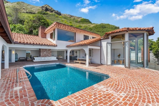 rear view of house featuring a patio area, an outdoor pool, an outdoor hangout area, and a tile roof