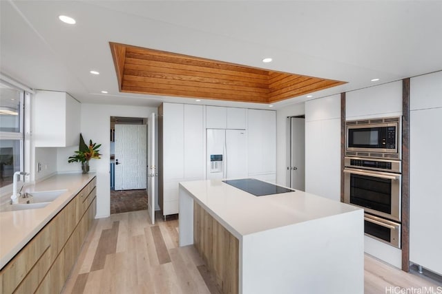 kitchen with light wood finished floors, recessed lighting, a sink, built in appliances, and modern cabinets