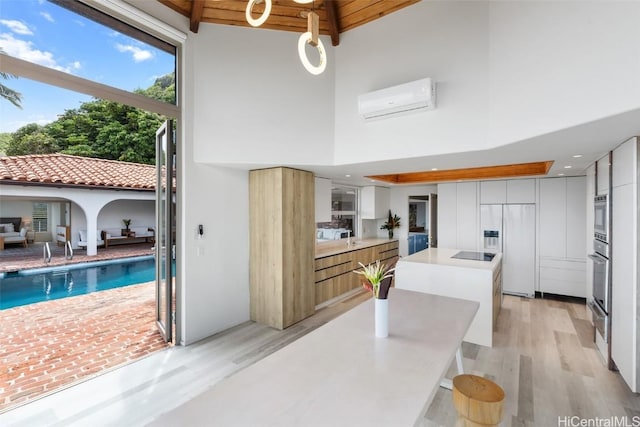 kitchen with built in appliances, light wood-style flooring, an AC wall unit, and modern cabinets