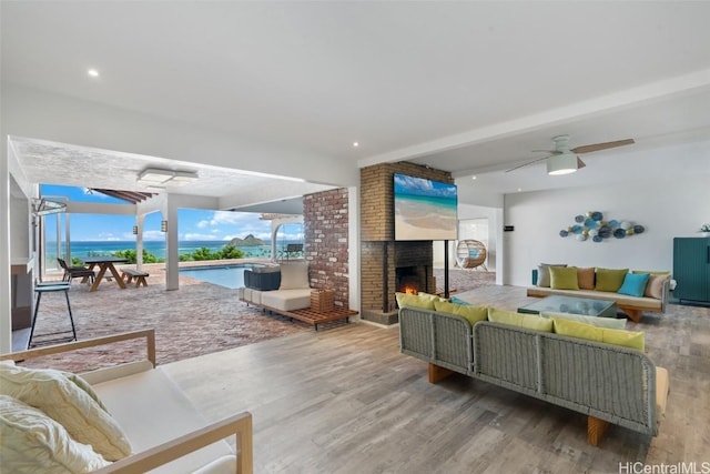 living room featuring beamed ceiling, a brick fireplace, wood finished floors, and a sunroom