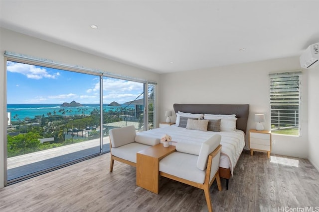 bedroom with access to exterior, an AC wall unit, and wood finished floors