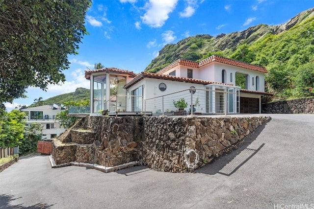 mediterranean / spanish house with a mountain view, driveway, and a tile roof