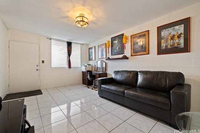 living room with concrete block wall and light tile patterned floors