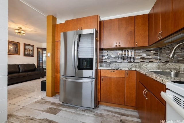 kitchen featuring brown cabinetry, smart refrigerator, backsplash, and a sink