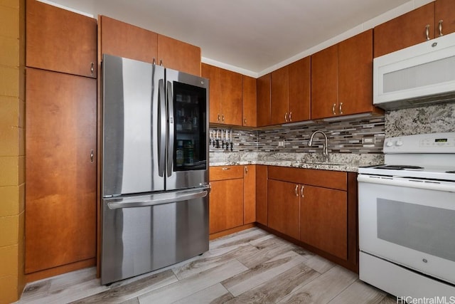 kitchen featuring white appliances, light wood finished floors, backsplash, and a sink