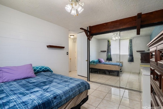 bedroom with light tile patterned floors, a textured ceiling, and a closet