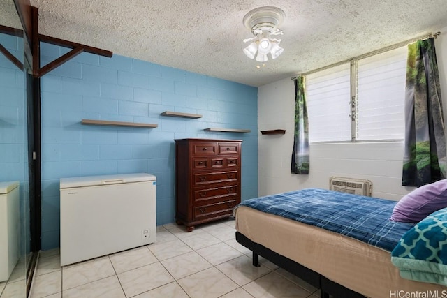 bedroom with light tile patterned floors, a textured ceiling, concrete block wall, and white fridge