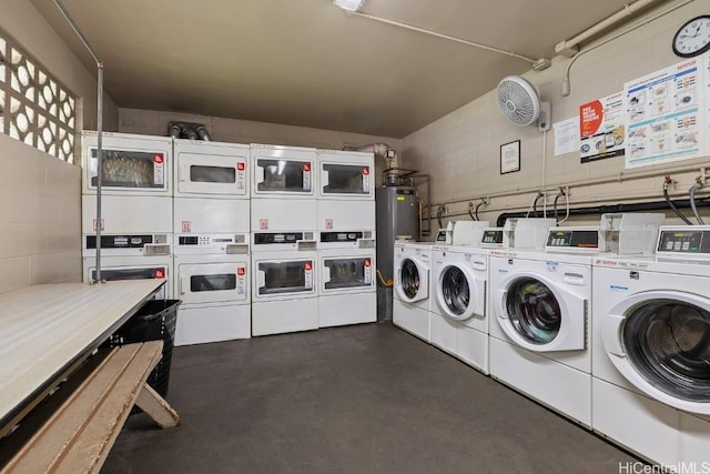 community laundry room with a garage, separate washer and dryer, stacked washer and clothes dryer, and concrete block wall