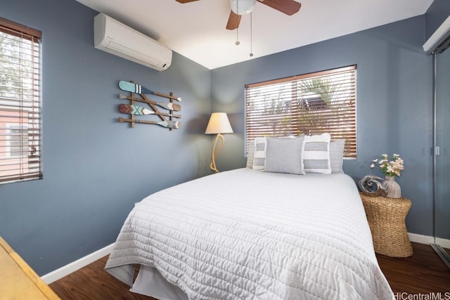 bedroom with multiple windows, a wall unit AC, and wood finished floors