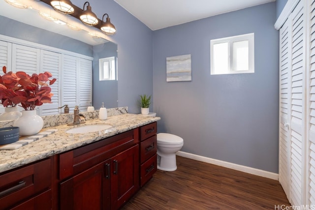 bathroom with vanity, wood finished floors, baseboards, a closet, and toilet