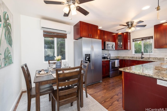 kitchen featuring decorative backsplash, a wall unit AC, appliances with stainless steel finishes, and reddish brown cabinets