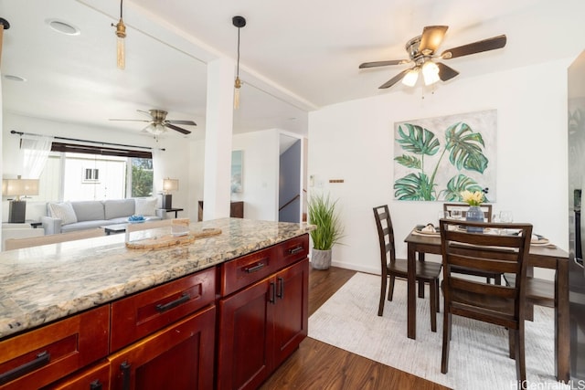 kitchen with dark brown cabinets, baseboards, light stone countertops, ceiling fan, and dark wood-style flooring