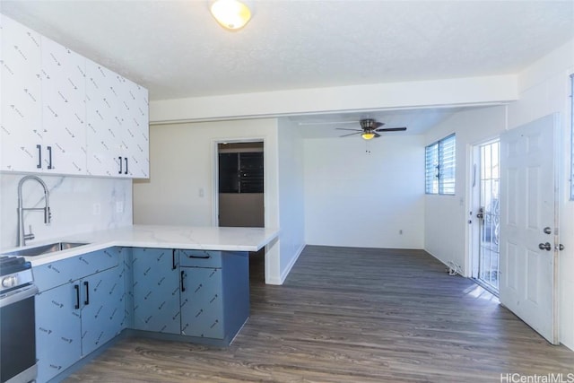 kitchen featuring dark wood-style floors, a peninsula, light countertops, and a sink