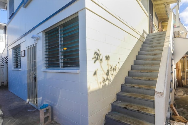 view of side of home featuring concrete block siding and stairs