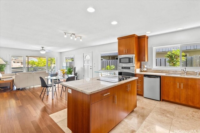 kitchen featuring a sink, a kitchen island, appliances with stainless steel finishes, and brown cabinetry