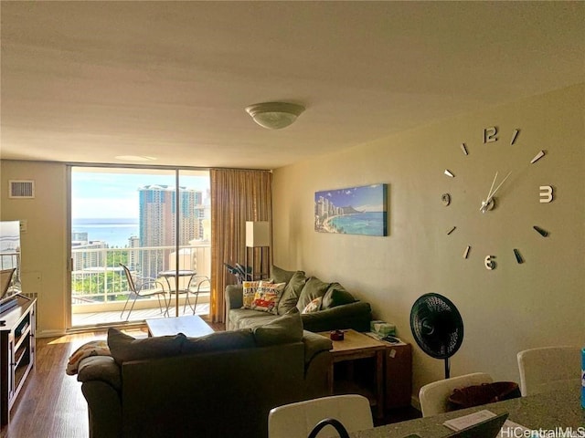 living room featuring a city view, floor to ceiling windows, wood finished floors, and visible vents