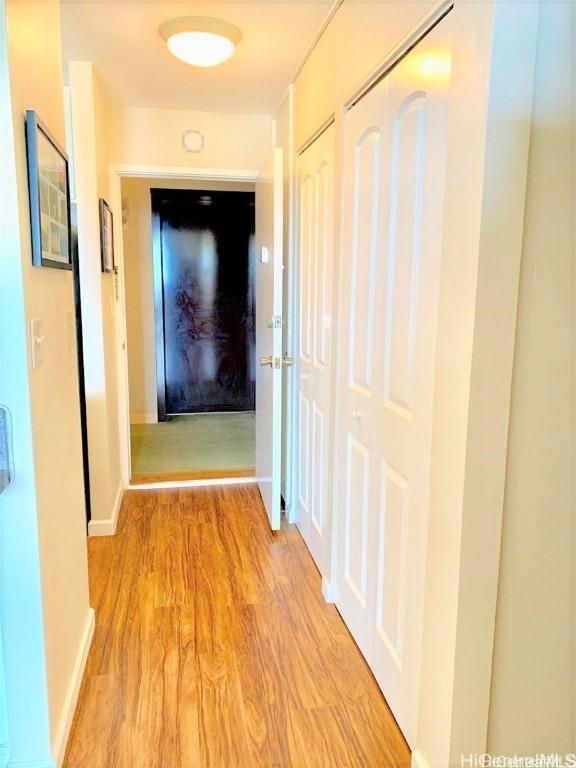 hallway featuring baseboards and wood finished floors