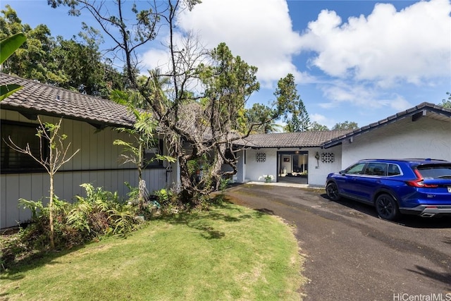 view of front of home featuring a front lawn, driveway, and a tile roof