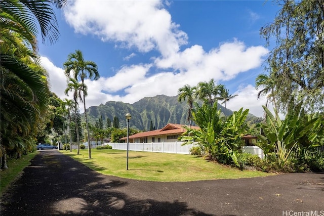 view of property's community with a lawn, a mountain view, and fence