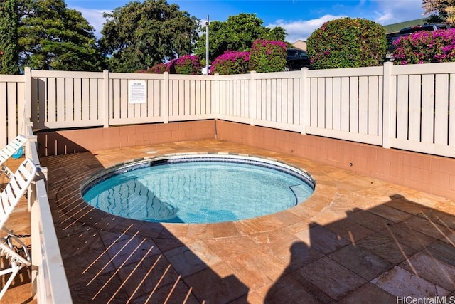 view of swimming pool with fence and a hot tub